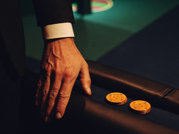 A guest's hand resting on a table rail beside a short stack of chips